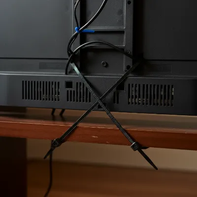 Close-up view of heavy-duty zip ties securing a TV to a wooden stand, demonstrating a DIY method