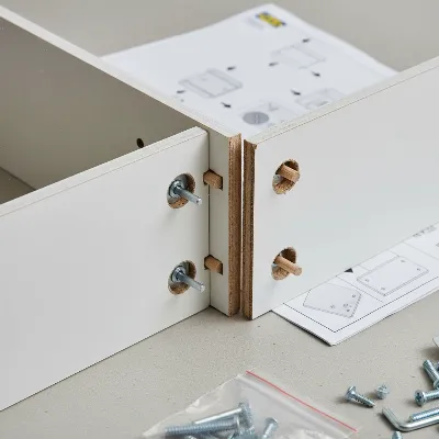 Close-up of Ikea Besta assembly, showing particleboard and melamine foil finish with hardware components.
